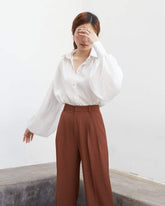 Wide-leg silk pants with high-rise waist and tailored pleats for effortless sophistication